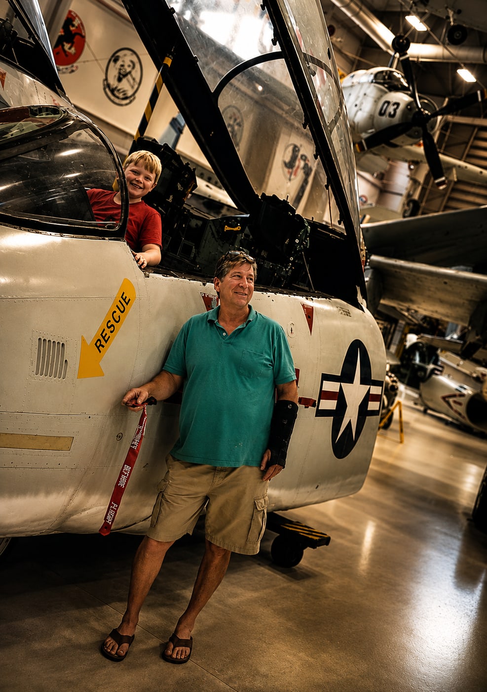 Mark Vest beside a U.S. Navy fighter jet, with his grandson in the cockpit