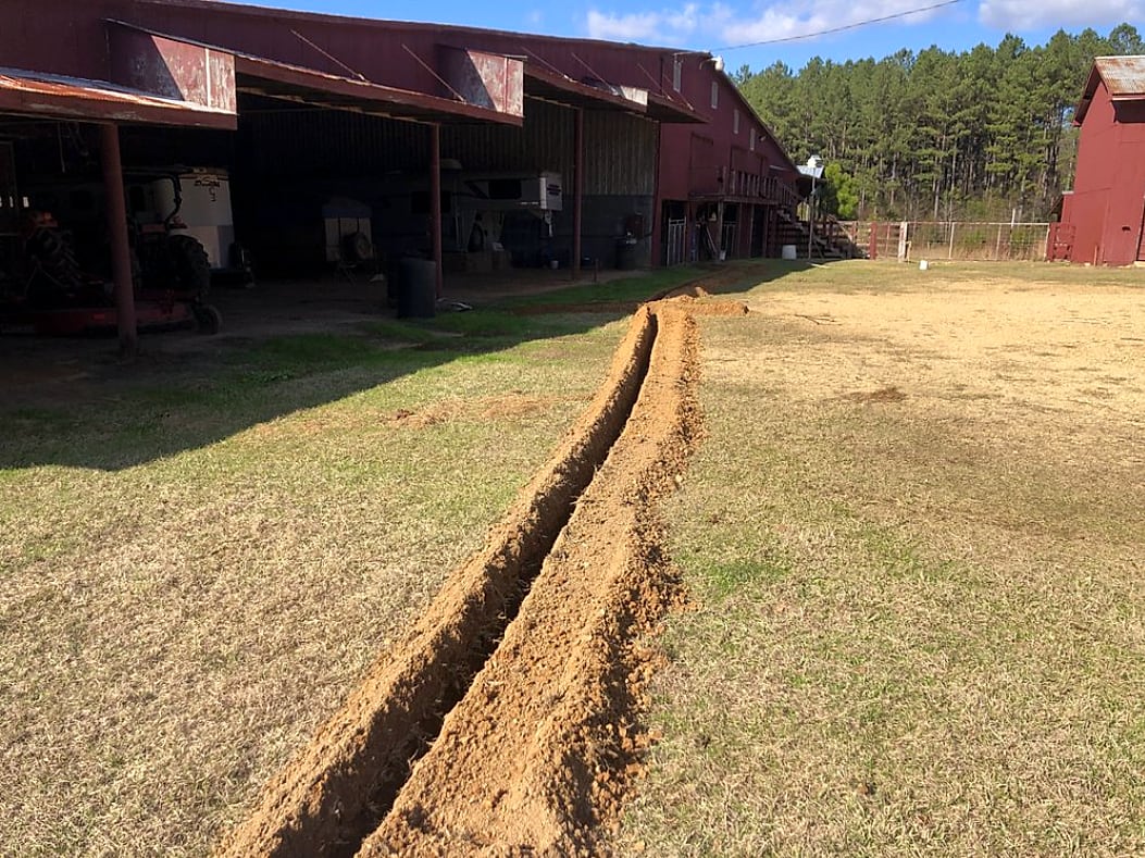 Trench dug across a field for a new water line to a barn